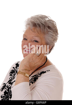 A lovely senior woman in her seventies holding her hand on her face and smiling, isolated for white background. Stock Photo