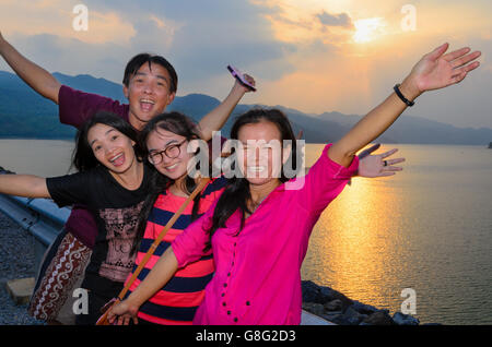 Group of people the family asian tourists are happy during the sunset over the lake at Khuean Sinakharin Dam in Kanchanaburi Stock Photo