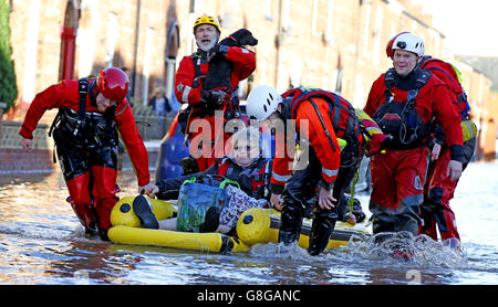 Rescue workers help a lady and her dog in Carlisle, after heavy rain from Storm Desmond tore through Britain, bringing strong winds and heavy rain which caused Cumbria to declare a major incident. Stock Photo