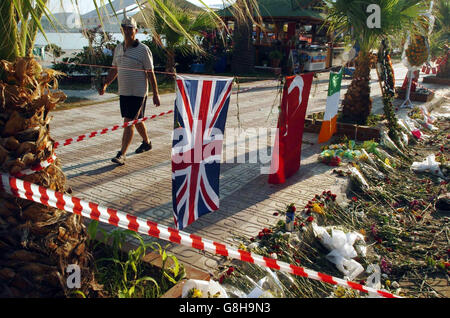 A man walks past the scene of Saturday's bomb blast, complete with flowers and tributes left in honour and in memory of the dead, which included one Briton. Several people were killed when a bomb went off on the minibus. Stock Photo