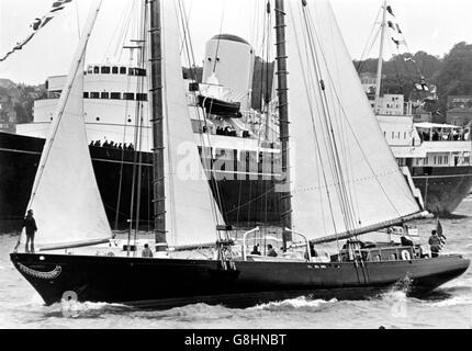 AJAXNETPHOTO. 4TH AUGUST,1974. COWES, ENGLAND. - REPLICA YACHT - THE AMERICAN SCHOONER AMERICA MINUS ITS BOWSPRIT, SAILS PAST THE ROYAL YACHT BRITANNIA DURING THE TALL SHIPS PARADE OF SAIL.  PHOTO:JONATHAN EASTLAND/AJAX  REF:AMERICA 1974 Stock Photo