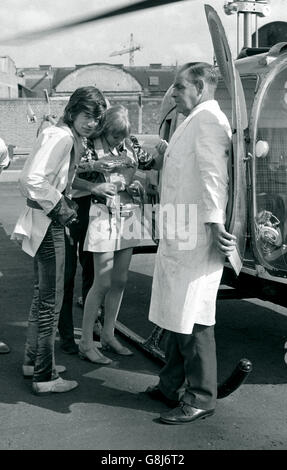 Mick Jagger, (left) of the Rolling Stones and his girlfriend, pop star, actress, Marianne Faithfull, have their life-jackets fitted before boarding a helicopter at Battersea Heliport. Stock Photo