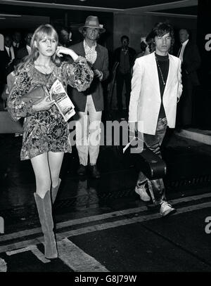 Mick Jagger, of the Rolling Stones, carrying a guitar case, and his singer friend Marianne Faithfull. Stock Photo