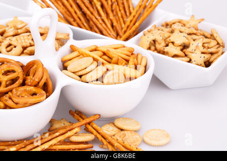Different salted crackers in bowls on white background. Stock Photo