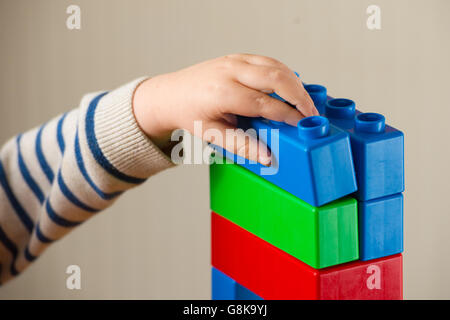 A preschool age child plays with plastic building blocks. Stock Photo