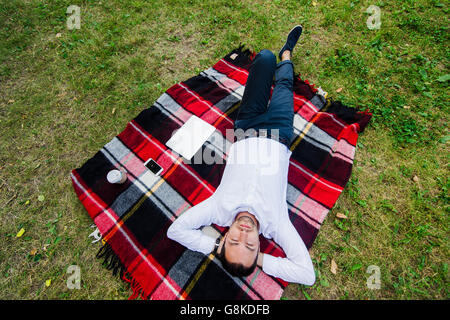 Happy young man with laptop relaxing on the grass, view from the top Stock Photo
