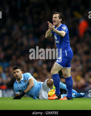 Manchester City's Sergio Aguero (left) lies on the ground after a challenge by Everton's Leighton Baines during the Capital One Cup, semi final, second leg at the Etihad Stadium, Manchester. Stock Photo