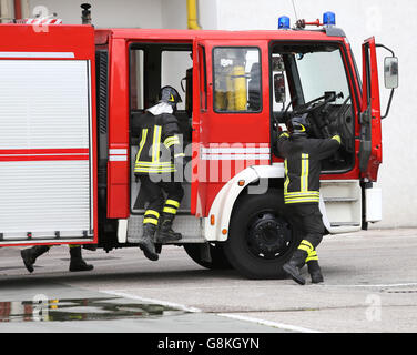 fire engine carrying two firefighters and equipment for fighting fire Stock Photo