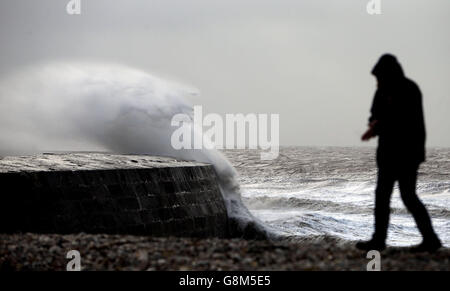 A man watches the waves crash against the harbour wall in Lyme Regis, Dorset as winds of nearly 100mph battered Britain after Storm Imogen slammed into the south coast bringing fierce gusts and torrential downpours, Stock Photo