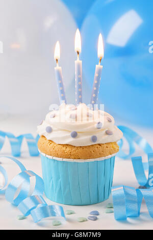 Blue cup cake with birthday candles and balloons Stock Photo