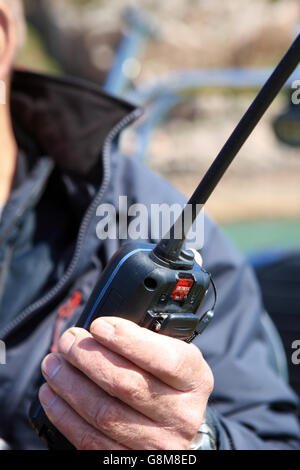 Man using hand held VHF radio on board a boat whilst at sea. Stock Photo