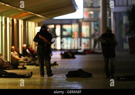 People playing the part of gunmen 'open fire' at a packed bus stop during a training exercise to test the response of the emergency services to a major firearms attack at the Intu Braehead shopping centre near Glasgow. Stock Photo