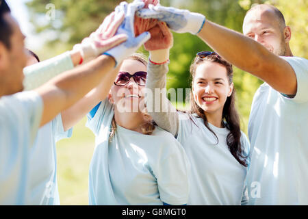 group of happy volunteers making high five in park Stock Photo