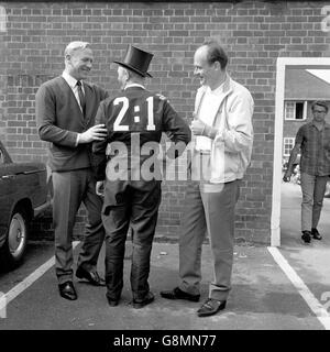 A West Germany fan dressed as a chimney sweep (a German symbol of good luck) is congratulated on his prediction for the World Cup Final scoreline by team advisor Bert Trautmann (l) and team doctor W. Gerhardt (r) as they meet on the morning of the final outside the team's hotel Stock Photo