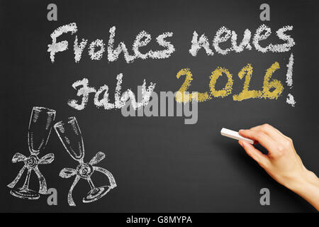 Hand writes in German 'Frohes neues Jahr 2016!' (Happy new year 2016!) on blackboard Stock Photo
