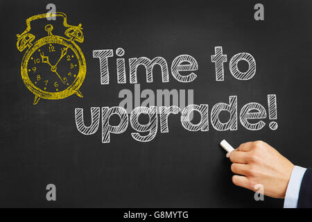 Hand writes "Time to upgrade" on blackboard Stock Photo