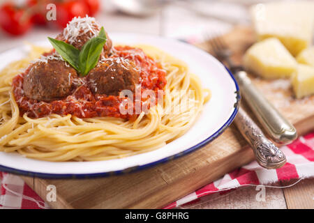 A plate with spaghetti with meatballs, topped with some grated parmesan cheese and basil. Stock Photo