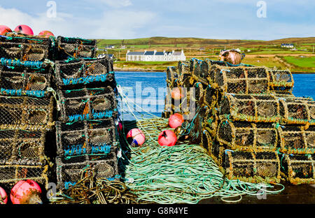 Lobster, cray and crab pots stacked up on the pier in Portmagee, County Kerry, Ireland.  Valentia Island in the background Stock Photo