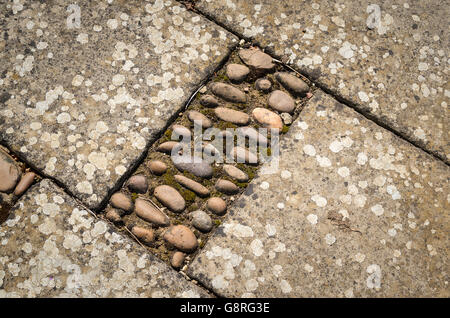 Inlaid pebbles add variety to a plain paved pathway or patio in a Cotswold garden Stock Photo