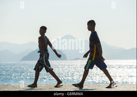 RIO DE JANEIRO - APRIL 3, 2016: Young Brazilians walk in silhouette on the boardwalk at Copacabana Beach on a misty morning. Stock Photo