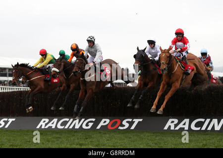 Horses jump a fence in the Ultima Handicap Chase (Grade 3) during Champion Day of the 2016 Cheltenham Festival at Cheltenham Racecourse. Stock Photo