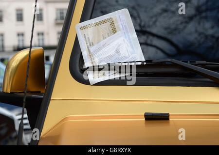 A parking ticket placed on a 6x6 Mercedes G 63 from Saudi Arabia, which is one of three gold cars parked on Cadogan Place in Knightsbridge, London. Stock Photo