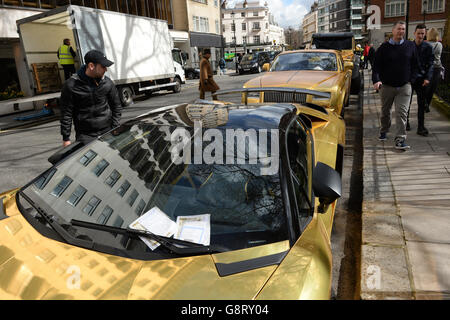 Three gold cars from Saudi Arabia (back-front) a 6x6 Mercedes G 63, Rolls-Royce Phantom Coupe and Lamborghini Aventador have received parking tickets on Cadogan Place in Knightsbridge, London. Stock Photo