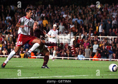 Soccer - UEFA Champions League - Group B - Arsenal v FC Thun - Highbury. Arsenal's Dennis Bergkamp scores the winning goal as FC Thun's Selver Hodzic (l) looks on Stock Photo