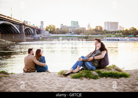 Group of tourists taking a break on water's edge in city Stock Photo