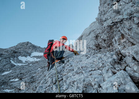 Mountaineer climbing steep wall in mountain range