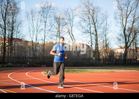 Young man jogging on running track in stadium Stock Photo