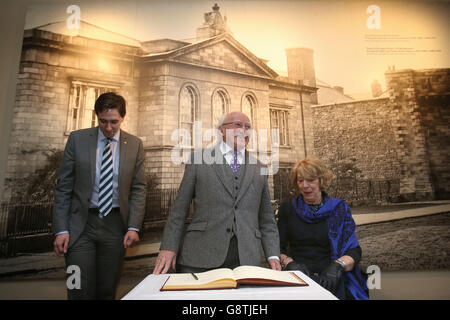 President Michael D Higgins (centre) and his wife Sabina Coyne with Simon Harris TD, the Minister of State at the Departments of Finance (left) as he signs the visitors book at the opening of the new visitor centre in Kilmainham Gaol, Dublin. Stock Photo