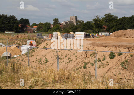 New house building on a green field site. Ground preparation. St. Mary's Parish Church, Stalham, behind centre. Norfolk. Stock Photo