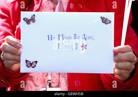 A member of the public holds up a card for Queen Elizabeth II as she visits the Royal Mail Windsor delivery office in Berkshire to mark the 500th anniversary of the postal service as the monarch begins her 90th birthday celebrations. Stock Photo