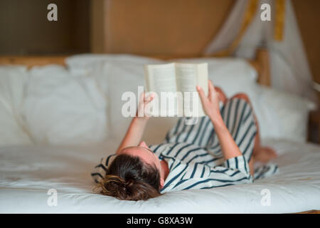 Beautiful woman reading book in bed relaxing Stock Photo
