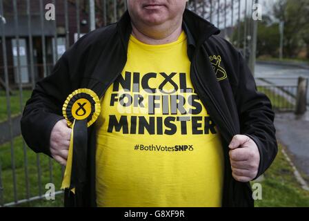 An SNP supporter outside Broomhouse Community Hall polling station in Glasgow, Scotland, as the polls open in the Scottish Parliament election. Stock Photo