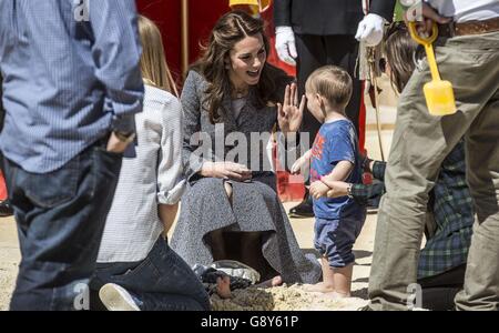 The Duchess of Cambridge plays with a youngster in a sand pit as she views Hampton Court's Magic Garden, marking the official opening of the palace's new children's play area. Stock Photo