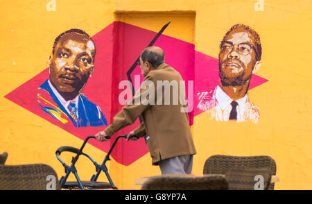 Las Palmas, Gran Canaria, Canary Islands, Spain, 30th June 2016. A man walks past a wall painted with images of Martin Luther King and Malcolm X. The graffiti on the wall of a vacant building lot changes on almost a weekly basis. Credit:  Alan Dawson News/Alamy Live News Stock Photo