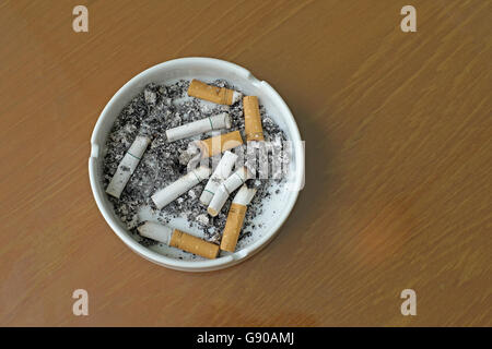 smoked cigarettes in white ashtray on wooden table Stock Photo