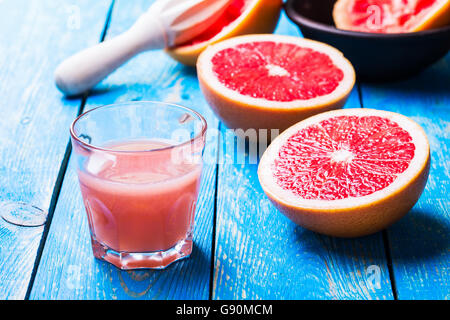 Glass of fresh grapefruit juice and fresh fruits on blue wooden table Stock Photo