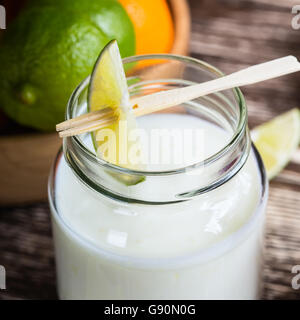 Delicious homemade organic yoghurt with lime juice  in a glass jar on wooden table Stock Photo
