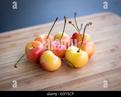 Beautiful, sweet, and delicious Rainier cherries on a bamboo cutting board. Stock Photo