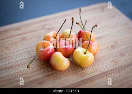 Beautiful, sweet, and delicious Rainier cherries on a bamboo cutting board. Stock Photo