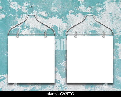 Close-up of two square blank frames hanged by clothes hanger against blue and white scratched wall background Stock Photo