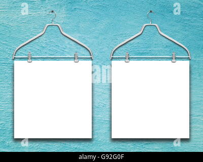 Close-up of two square blank frames hanged by clothes hanger against blue plaster wall background Stock Photo