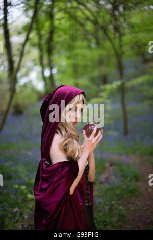 A young woman modeling for a Fantasy makeover 'game of thrones' style outdoors photography : Goddess / Priestess  in the forest. With a crystal ball in her hand, UK Stock Photo