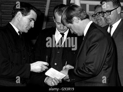 David McCallum who plays Illya Kuryakin in the BBC television series, 'The Man From U.N.C.L.E', signs autographs before leaving for Rome. (fans pictured in background). Stock Photo