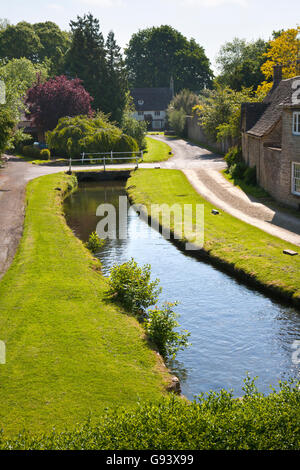 The infant River Thames passes idyllic Cotswold cottages in Ashton Keynes, Wiltshire, UK Stock Photo