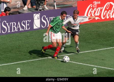 Soccer - World Cup France 98 - Second Round - Germany v Mexico. Mexico's Cuauhtemoc Blanco (left) takes on Germany's Christian Worns (right) in front of a Sybase Advertising Board Stock Photo