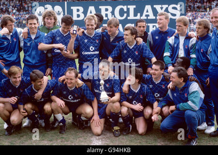 Chelsea players celebrate with the Division Two championship trophy after clinching the title with a 3-1 victory: (back row, l-r) Dave Mitchell, Kevin Hitchcock, Dave Beasant, Joey McLoughlin, Kerry Dixon, ?, ? Tony Dorigo, ?, ?, Gordon Durie, John Bumstead, ?; (front row, l-r) Gareth Hall, Kevin Wilson, Peter Nicholas, Graham Roberts, Kevin McAllister, Steve Clarke, Clive Wilson, assistant manager Ian Porterfield (front) Stock Photo